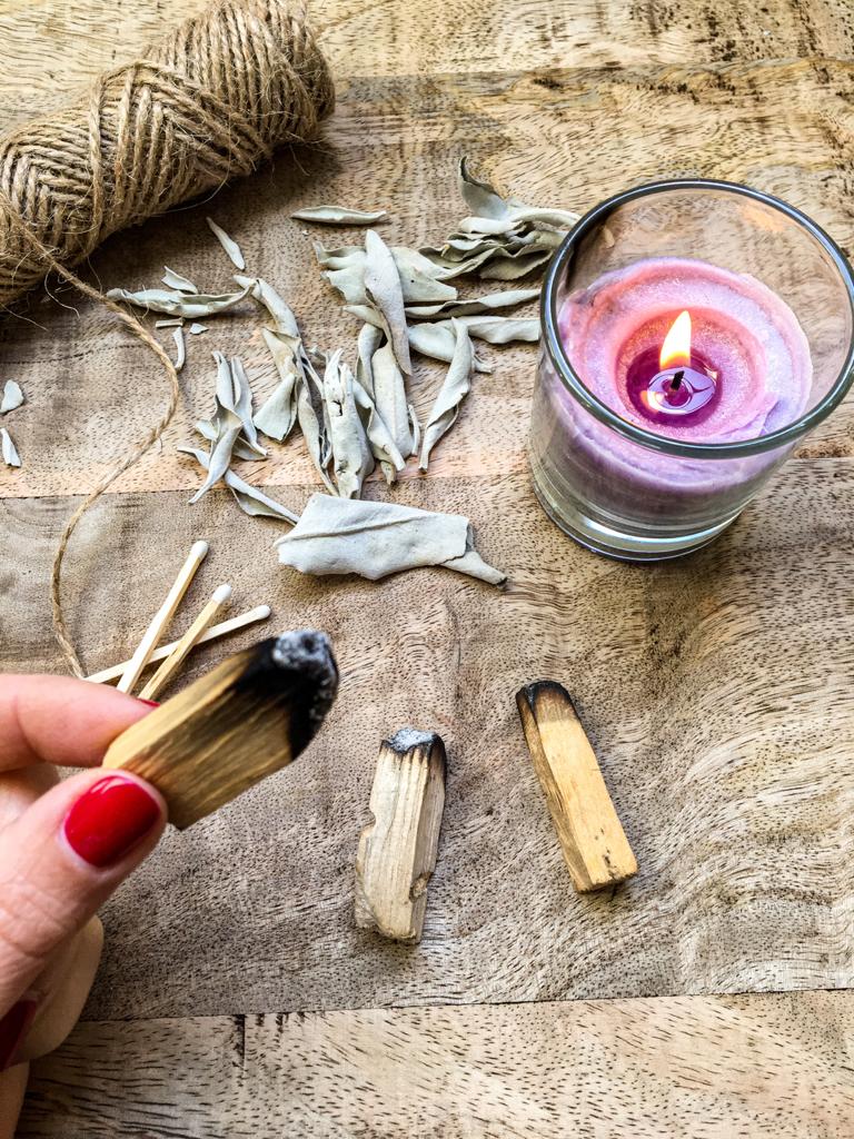 palo santo che viene acceso con candele e salvia bianca per rituale smudging