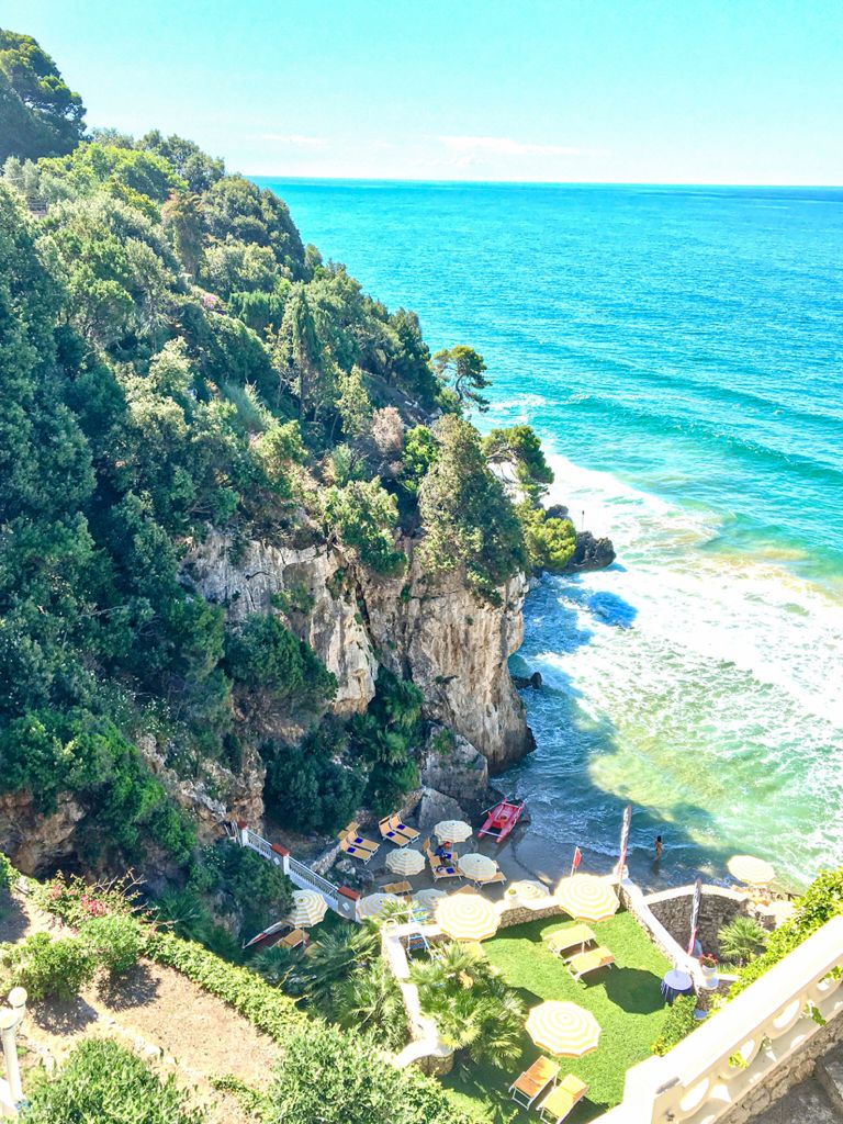 baia privata con acqua cristallina e roccia a strapiombo ricoperta di vegetazione verde