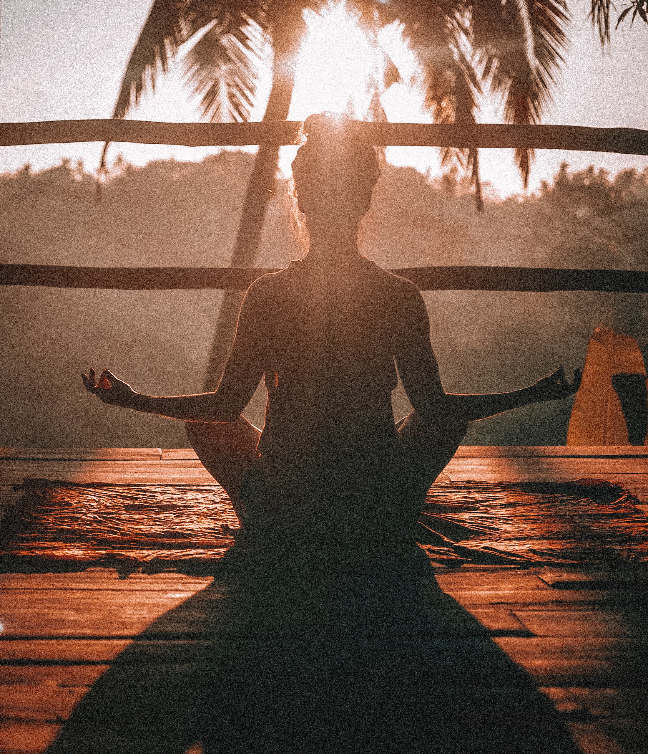 ragazza di spalle che medita al tramonto in una capanna di legno