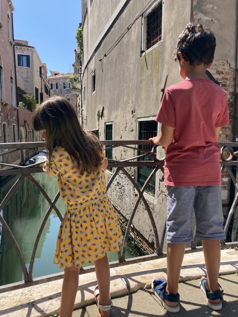 two kids looking at the canal from the top of a bridge in Venice