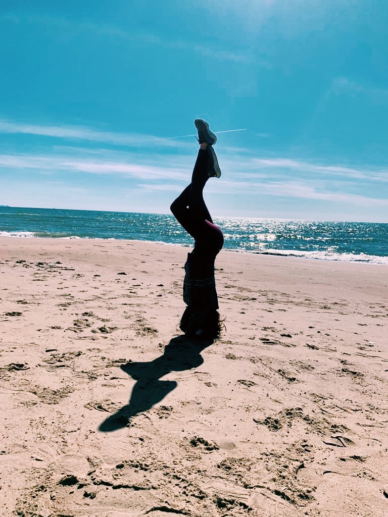 ragazza fa la verticale in riva al mare 